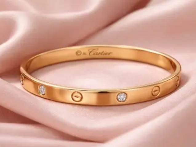 Cartier Love Bangle gold tone stainless steel anti tarnish bracelet with crystal accents on pink satin